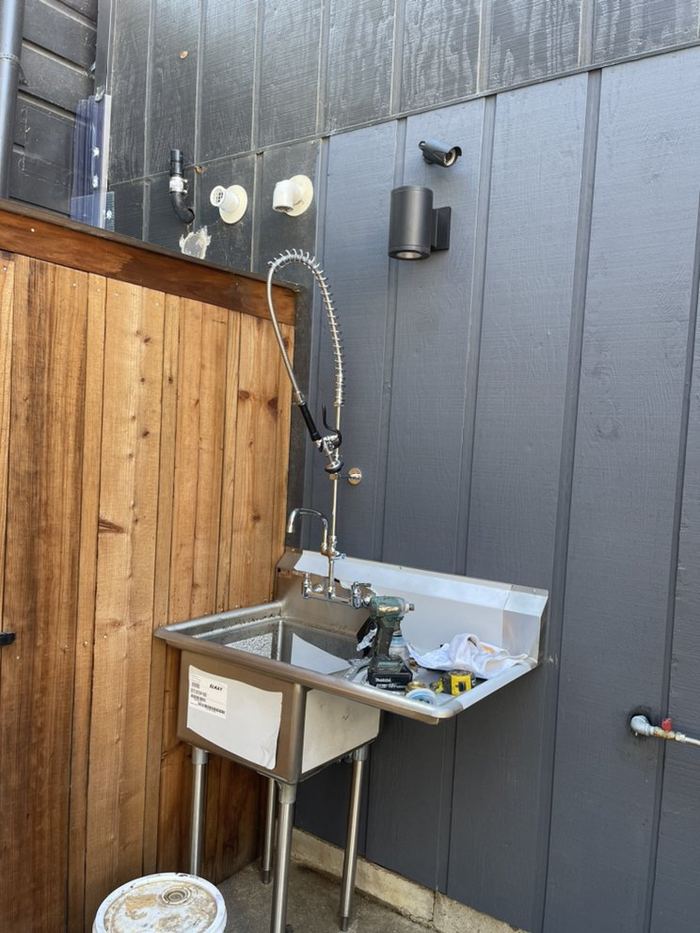 Completed stainless commercial utility sink and pre-rinse faucet installation